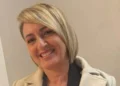 Ritratto di Nuccia Quattrocchi, maestra di danza, sorridente con cappotto chiaro su sfondo neutro.