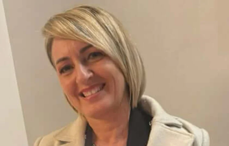 Ritratto di Nuccia Quattrocchi, maestra di danza, sorridente con cappotto chiaro su sfondo neutro.