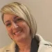 Ritratto di Nuccia Quattrocchi, maestra di danza, sorridente con cappotto chiaro su sfondo neutro.