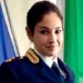 Ritratto in primo piano di una donna in uniforme della Polizia di Stato, davanti a bandiere italiana ed europea.