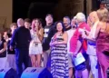 Gruppo di persone sul palco durante una serata musicale, con luci colorate e monitor audio in primo piano