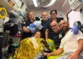 Operatori del 118 in ambulanza con la neomamma in coperta termica, il compagno e il neonato in braccio a un'operatrice.
