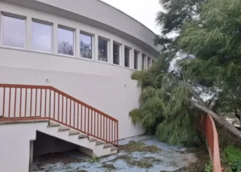 Edificio della piscina comunale di Modica con facciata curva, scala esterna e albero inclinato nel cortile in stato di abbandono