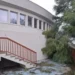 Edificio della piscina comunale di Modica con facciata curva, scala esterna e albero inclinato nel cortile in stato di abbandono