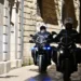 Due agenti di polizia in moto percorrono una stretta strada del centro storico
