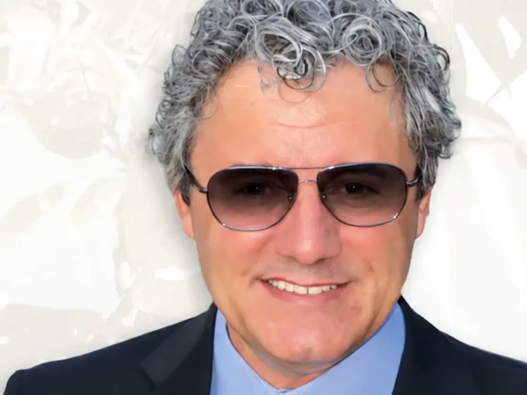 Francesco Di Benedetto, professore di Ispica: capelli grigi ricci, occhiali da sole, giacca scura e camicia azzurra.