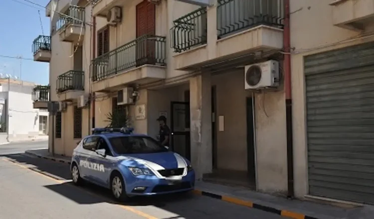 Auto della Polizia di Stato parcheggiata davanti all'ingresso del Commissariato di Comiso, con agente in divisa sul portone