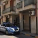 Auto della Polizia di Stato parcheggiata davanti all'ingresso del Commissariato di Comiso, con agente in divisa sul portone