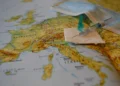 Siringa con ago su una garza sterile e una mascherina chirurgica, sopra una cartina geografica dell'Europa