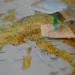 Siringa con ago su una garza sterile e una mascherina chirurgica, sopra una cartina geografica dell'Europa