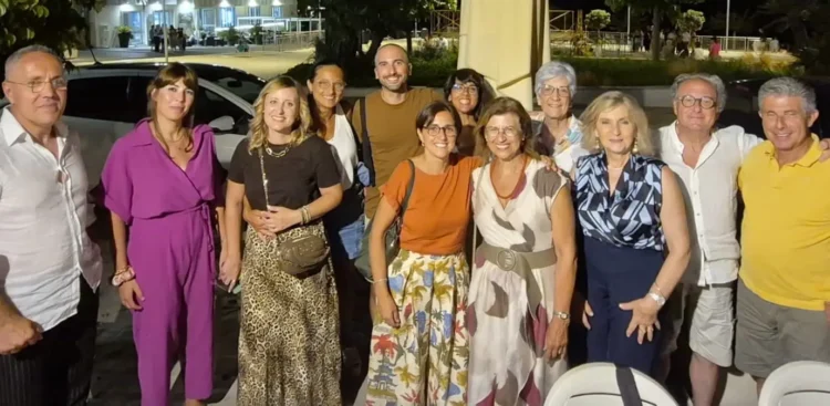 Gruppo di ex studenti e insegnanti in posa di sera davanti a un locale di Marina di Modica