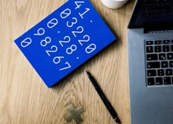 Tavola blu con numeri disposti in sequenza, accanto a laptop, penna e simbolo matematico su una scrivania.