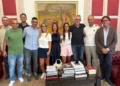 Gruppo riunito in una sala d'onore con boiserie rosse e un dipinto alle spalle, durante un ricevimento a Palazzo di Città.
