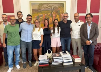 Gruppo riunito in una sala d'onore con boiserie rosse e un dipinto alle spalle, durante un ricevimento a Palazzo di Città.