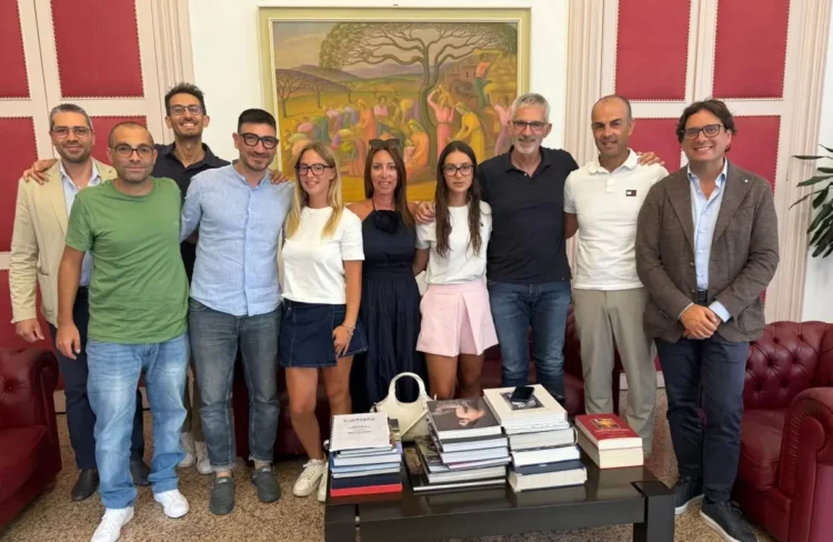 Gruppo riunito in una sala d'onore con boiserie rosse e un dipinto alle spalle, durante un ricevimento a Palazzo di Città.