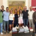 Gruppo riunito in una sala d'onore con boiserie rosse e un dipinto alle spalle, durante un ricevimento a Palazzo di Città.