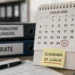 Calendario da tavolo con il 31 luglio cerchiato in rosso, cartellino giallo con scritta "Scadenza 31 luglio" e raccoglitori etichettati "Rottamazione quinquies" e "Rate"
