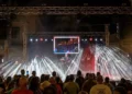 Folla davanti al palco illuminato della Sagra del Pesce di Pozzallo in piazza delle Rimembranze durante una serata di agosto 2026