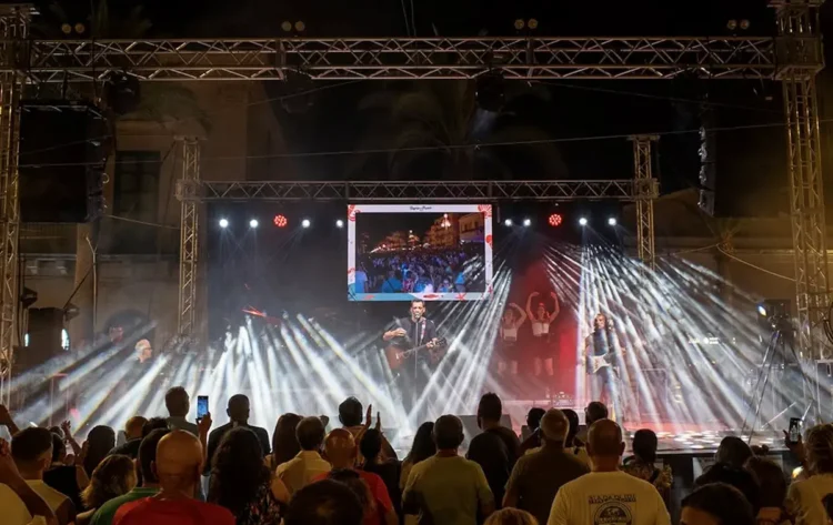 Folla davanti al palco illuminato della Sagra del Pesce di Pozzallo in piazza delle Rimembranze durante una serata di agosto 2026