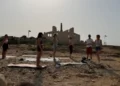 Gruppo di persone su tappetini da yoga davanti alle rovine della Fornace di Punta Pisciotto a Sampieri, Scicli