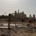Gruppo di persone su tappetini da yoga davanti alle rovine della Fornace di Punta Pisciotto a Sampieri, Scicli