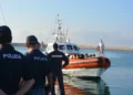 Agenti di polizia osservano una motovedetta della Guardia Costiera con migranti a bordo in un porto siciliano