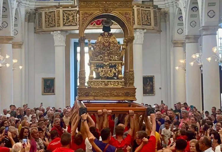 Portatori sollevano il simulacro di San Bartolomeo durante la Scinnuta, davanti ai fedeli nella chiesa di Giarratana.