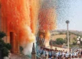 Portatori in maglietta azzurra sorreggono il simulacro della Madonna della Neve tra nuvole di fumo arancione e coriandoli colorati davanti alla basilica di Giarratana