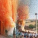 Portatori in maglietta azzurra sorreggono il simulacro della Madonna della Neve tra nuvole di fumo arancione e coriandoli colorati davanti alla basilica di Giarratana