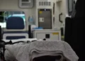 Barella con lenzuola ripiegate in un'ambulanza, sullo sfondo sfocato un sedile e apparecchiature sanitarie