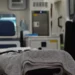 Barella con lenzuola ripiegate in un'ambulanza, sullo sfondo sfocato un sedile e apparecchiature sanitarie
