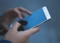Mano che tiene uno smartphone con schermo spento durante un disservizio della rete mobile