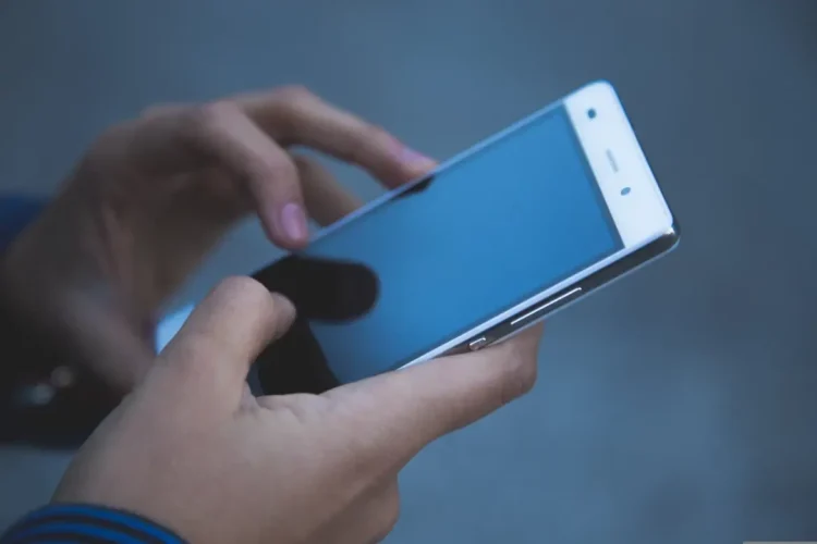 Mano che tiene uno smartphone con schermo spento durante un disservizio della rete mobile