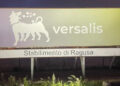 Insegna luminosa dello stabilimento Versalis di Ragusa fotografata di notte, con logo del leone stilizzato.
