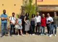Gruppo di persone davanti a una villetta dell'ex base Nato di Comiso, edificio con intonaco degradato sullo sfondo