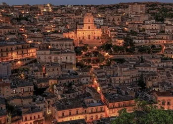 Veduta notturna del centro storico di Modica con il Duomo di San Giorgio illuminato tra le case.