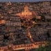 Veduta notturna del centro storico di Modica con il Duomo di San Giorgio illuminato tra le case.