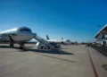 Aerei in sosta sul piazzale di un aeroporto, con scaletta mobile accostata e terminal sullo sfondo, cielo sereno