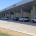 Facciata dell'aeroporto di Comiso con l'insegna Aeroporto Civile Pio La Torre e auto parcheggiate sotto la pensilina.
