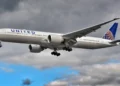 Aereo United Airlines in fase di atterraggio con carrello abbassato, cielo nuvoloso sullo sfondo