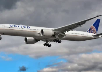 Aereo United Airlines in fase di atterraggio con carrello abbassato, cielo nuvoloso sullo sfondo