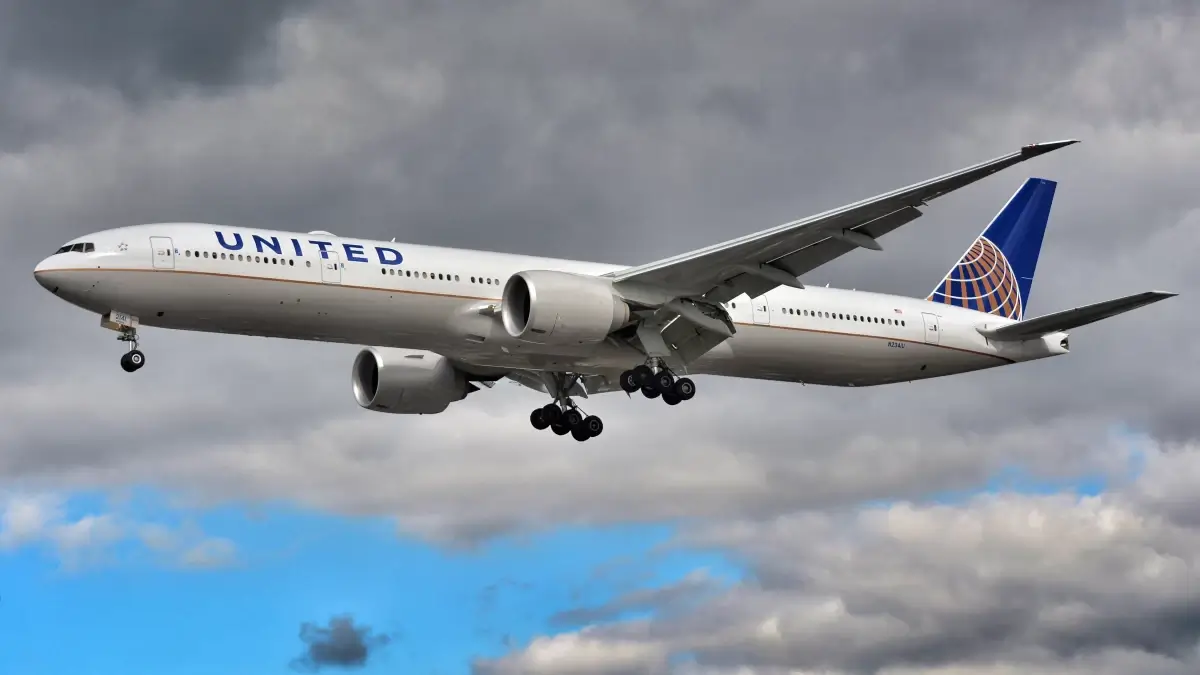 Aereo United Airlines in fase di atterraggio con carrello abbassato, cielo nuvoloso sullo sfondo