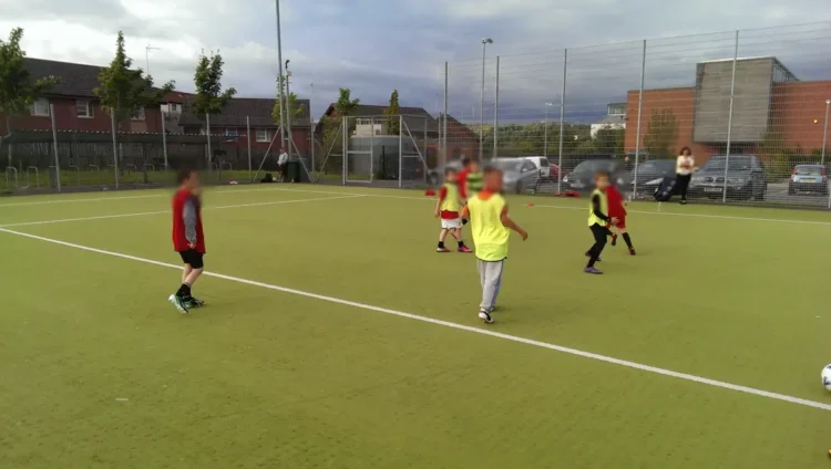 Un gruppo di ragazzi si allena su un campo da calcio a cinque con casacche gialle e rosse