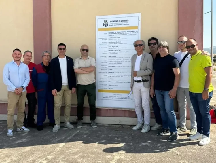 Gruppo di persone davanti al cartello di cantiere del Comune di Comiso per la riqualificazione della zona artigianale