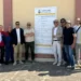 Gruppo di persone davanti al cartello di cantiere del Comune di Comiso per la riqualificazione della zona artigianale