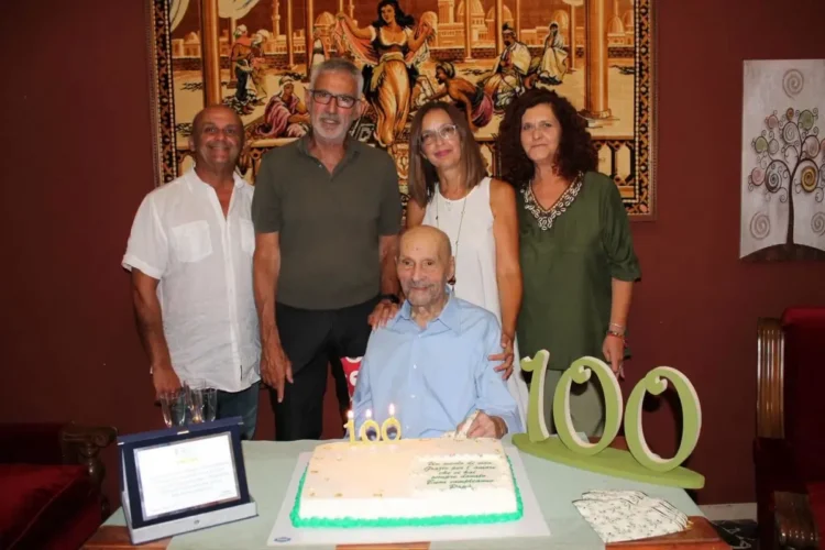 Giuseppe festeggia 100 anni a Ragusa davanti alla torta con il numero 100, insieme ad alcuni familiari