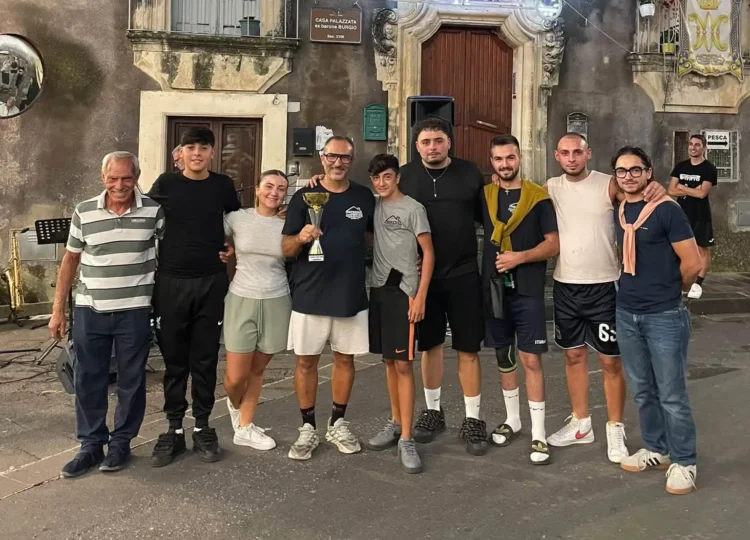 Cinque uomini in maglia azzurra con una coppa dopo il torneo di calcio balilla umano a Monterosso Almo