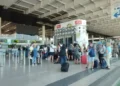 Passeggeri con trolley in fila ai banchi check-in 16-20 nel terminal dell'aeroporto di Catania