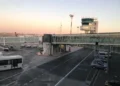 Piazzale dell'aeroporto di Catania con torre di controllo, finger, bus navetta e auto della Polizia all'alba