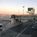 Piazzale dell'aeroporto di Catania con torre di controllo, finger, bus navetta e auto della Polizia all'alba